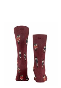 Bordeauxfarbene Socken mit einem sich wiederholenden Muster von Nussknackerfiguren in verschiedenen Farben. Hergestellt aus weichem Stoff mit einem gerippten Bündchen oben.