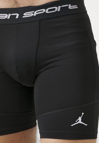 Fekete sport short, amely jól illeszkedik, szürke derékkal, amelyen a "Jordan Sport" felirat olvasható, valamint a bal oldalon egy fehér Jumpman logó található.