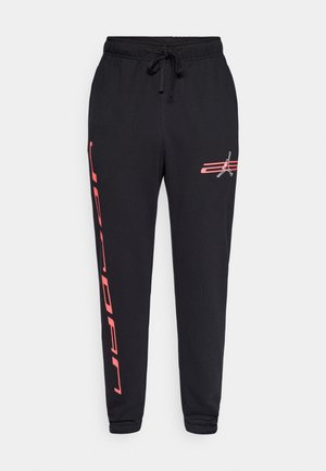 Pantalon de survêtement noir avec ceinture à cordon. Présente un texte "JORDAN" en rouge vif et un logo sur la jambe gauche. Matière douce en mélange de coton.