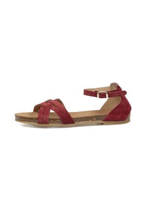 Sandalia plana de ante rojo con dos tiras delanteras cruzadas, tira en el tobillo con hebilla y suela con textura de corcho sobre fondo blanco.