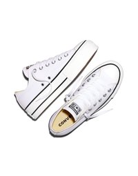 Baskets Converse All Star basses blanches avec détails à rayures noires, lacets blancs et écussons logo sur la languette et le talon.