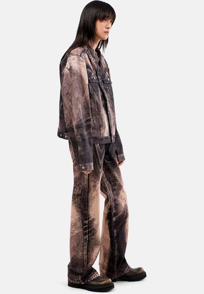 Giacca di jeans e pantaloni abbinati in tonalità terrose miste con un motivo testurizzato e usurato. Stivali neri chunky completano il look.