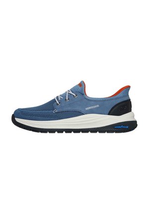 Zapatilla de malla azul y ante con suela de goma blanca y negra. Presenta detalles naranjas y cordones grises. Forma estilizada con un diseño de perfil bajo.