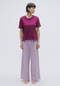 T-shirt en coton bordeaux associé à un pantalon de détente à larges rayures violet clair, doté d'une coupe ample et d'une texture douce.