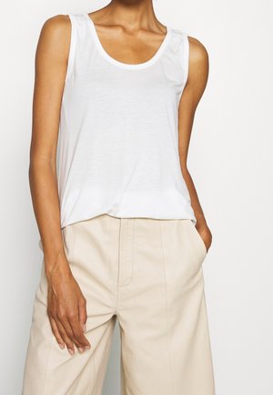 Weißes ärmelloses Tanktop mit einem runden Ausschnitt, das subtile Raffungselemente an den Schultern und einen weichen, leichten Stoff aufweist.