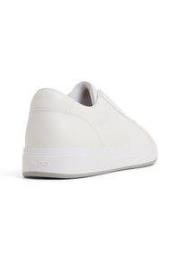 Zapatilla de cuero blanca con un acabado suave, forma redondeada y costuras en tono. Cuenta con una gruesa entresuela blanca y una sutil marca en el talón.