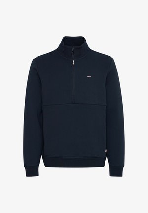 Mørkeblå genser med halv glidelås laget av mykt stoff, med høy krage og en liten logo på brystet. Ribbestrikkede mansjetter og nederkant.