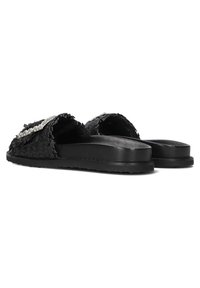 Zwarte platte sandalen met een geweven structuur, voorzien van een decoratieve bloemaccent. De zool is glad en plat, geschikt voor casual draag.