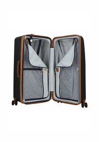 Valise rigide noire avec des accents bruns. L'intérieur est doté d'un tissu rayé avec des compartiments zippés et des poches en maille pour une meilleure organisation.