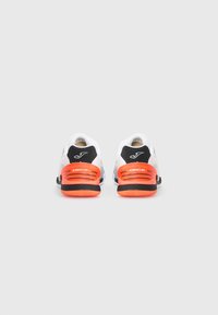 White athletic shoes with black and orange accents, featuring a textured sole and perforated design for breathability.