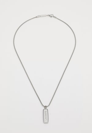 Collana in argento con pendente rettangolare inciso con "LACOSTE". La catena è finemente collegata e il pendente presenta una finitura liscia.