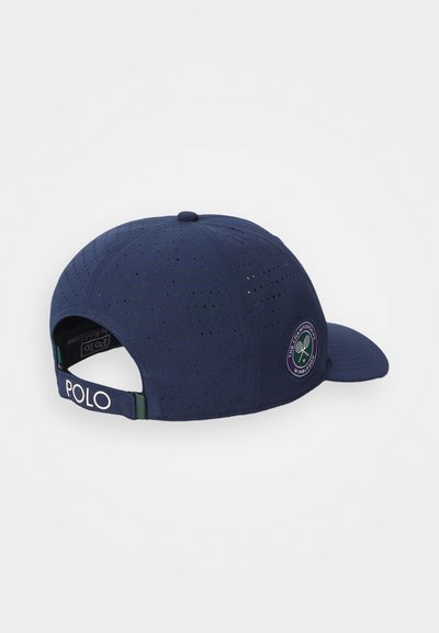 Căciulă bleumarin din material perforat, cu cozoroc curbat și spate ajustabil. Are un patch cu logo-ul Wimbledon și textul "POLO" pe curea.