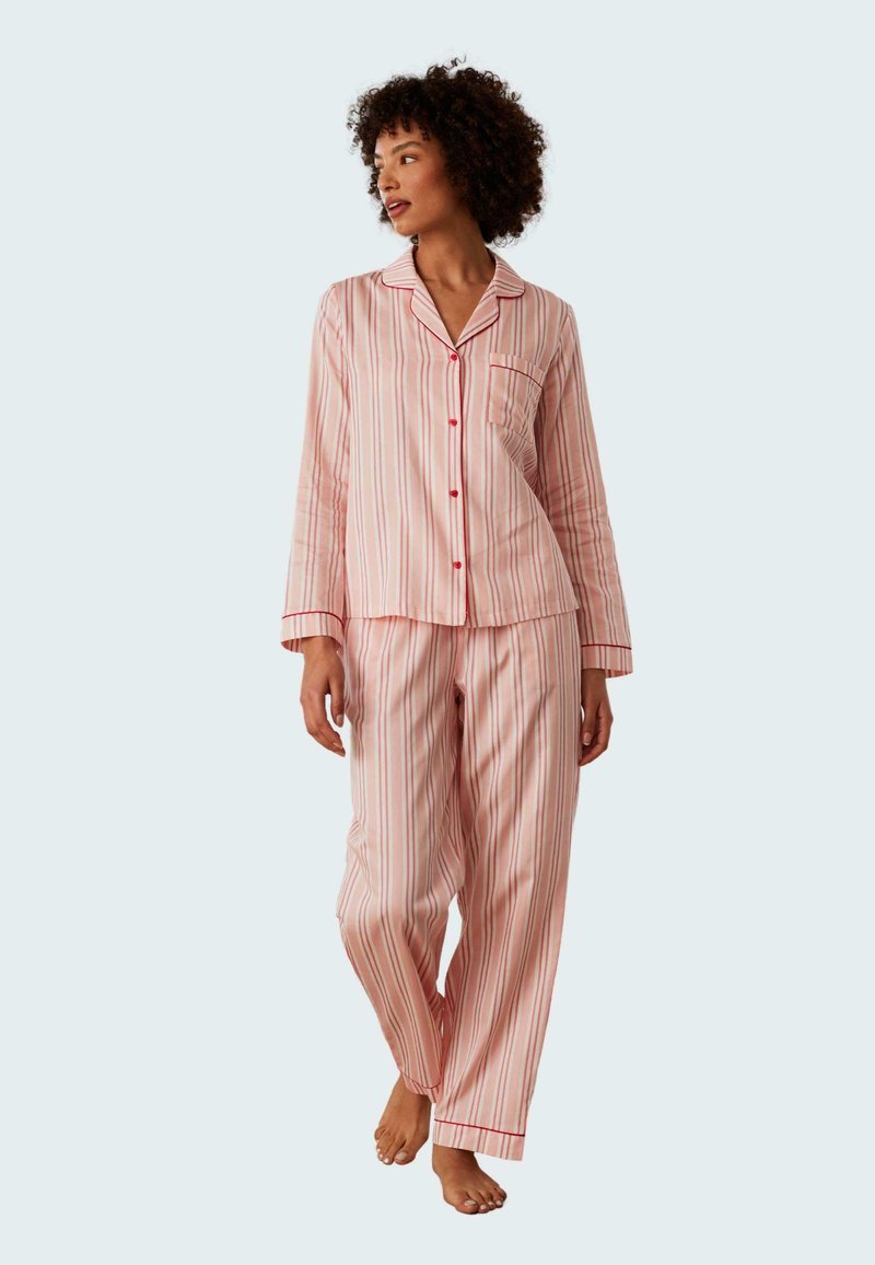 Randiga rosa pyjamaser i mjukt tyg, med långa ärmar, en knäppskjorta med ficka och vida byxor.