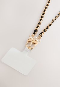 Melnas un zelta ķēdes siksniņa ar diviem skavām, pie kuras piestiprināts caurspīdīgs ID turētājs identifikācijas kartes izvietošanai.