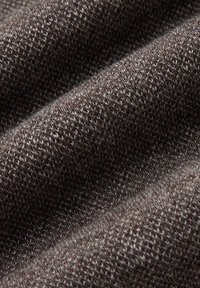 Brązowa tekstura tkaniny z wzorem dzianiny; charakteryzuje się miękkim, lekko puszystym dotykiem, ukazującym różnorodność ziemskich odcieni.