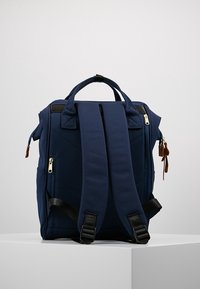 Tmavě modrý batoh s polstrovanými nastavitelnými popruhy, dvojitými zipy, koženými akcenty a prošívanou texturou hlavní látky.