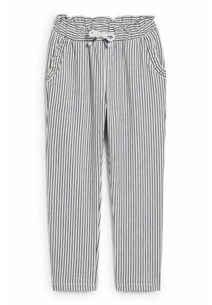 Pantalon blanc à rayures noires verticales, taille élastique avec cordon blanc, et deux poches avant avec bordure à volants.