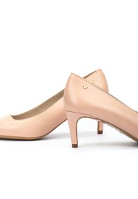 Zapatos de tacón bajo de charol nude con puntera redondeada y detalles en dorado en la parte trasera. Superficie lisa, diseño versátil.