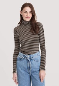 Gestreifter Rollkragenpullover in Dunkelbraun und Beige, kombiniert mit hellblauen, hochgeschnittenen Jeans mit gebundenem Gürtel und lockerer Passform.