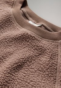 Brown fleece sweatshirt with a soft, textured surface and ribbed crew neckline shown in close-up.