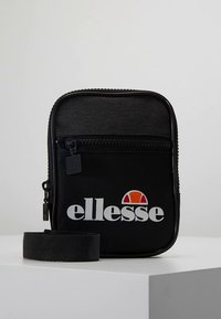 Schwarze Reißverschlusstasche aus strapazierfähigem Stoff, mit einer Fronttasche, einem verstellbaren Riemen und einem auffälligen weißen "ellesse"-Logo mit orangefarbenem Akzent.
