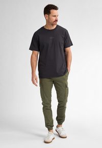 Mørkegrå bomulds T-shirt med rund hals, parret med olivengrønne cargo bukser med flere sidelommer, og hvide sneakers.