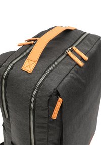 Mochila de tela negra con acentos de cuero naranja, que presenta cremalleras dobles y un asa superior acolchada. Superficie texturizada y forma estructurada.