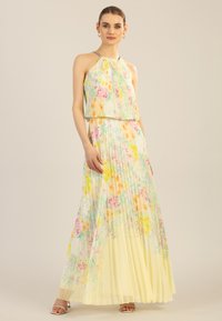Faltiges Maxikleid mit Halterneck, geschichteter Gestaltung und einem floralen Muster in Pastellfarben, hauptsächlich Gelb, Rosa und Grün.