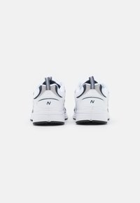 Scarpe da ginnastica bianche con accenti blu navy, sovrapposizioni testurizzate e collare imbottito, dotate di suola in gomma e un passante sul tallone.