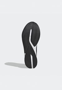 Suola di scarpa sportiva nera con una superficie testurizzata, caratterizzata da una linea di accento bianca e scanalature flessibili per trazione e supporto.