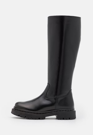 Wysoki czarny skórzany but z masywną podeszwą typu lug i zaokrąglonym noskiem, elegancki design oraz subtelne przeszycia na białym tle.