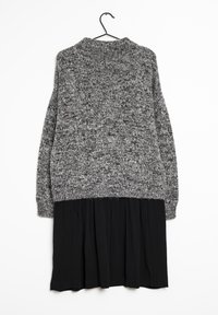 Harmaa neulepusero, jossa on pitkät hihat ja pyöreä pääntie, kerroksittain mustan laskostetun hameen päällä. Rakennekangas, jossa on vastakkaiset värit.