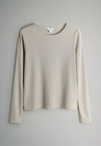 Top met lange mouwen met strepen in beige en crème. Voorzien van een ronde hals, een zachte textuur en een relaxte pasvorm met zijsplitten aan de zoom.
