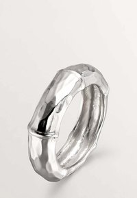 Anillo de plata metálica con un diseño inspirado en el bambú, que presenta una textura martillada y un interior suave, enfatizando una forma redondeada y escultórica.
