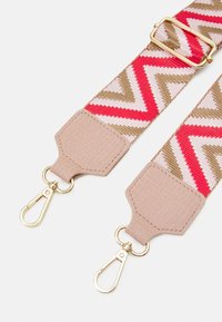 Vävd rem med zigzagmönster i röd, rosa och beige. Har ljusbeiga, strukturerade läderändar och detaljer i guld.