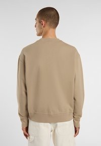 Beige katoenen sweatshirt met lange mouwen, ronde hals en geribbelde manchetten; zachte textuur; getoond vanuit de achterkant.