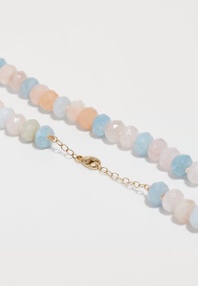 Náramok z korálkov so fasetovanými pastelovými drahokamami v modrej, ružovej a oranžovej farbe, so zlatým sponou vo forme homára a predlžovačom reťaze.