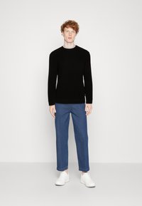 Schwarzer gestrickter Pullover mit Rundhalsausschnitt, kombiniert mit blauen geraden Jeanshosen und weißen Sneakers, minimalistisches Design, keine sichtbaren Muster.