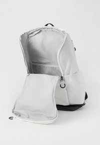 Zaino grigio con un ampio scomparto principale e una tasca frontale più piccola, dotato di tasche in rete e chiusura con zip. Tessuto resistente.