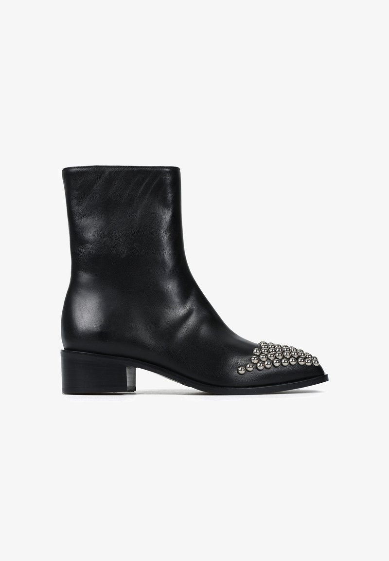 Czarne skórzane botki za kostkę na masywnym obcasie, z ostrym noskiem ozdobionym srebrnymi ćwiekami w skupionej formie. Gładka tekstura.