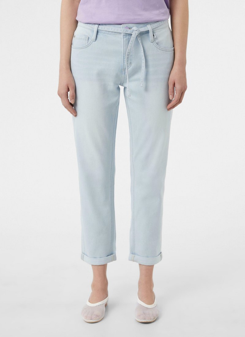 Jasnoniebieskie dżinsy o luźnym kroju, zwężające się nogawki, podwinięte mankiety, kieszenie z przodu oraz pas z dopasowanego materiału.