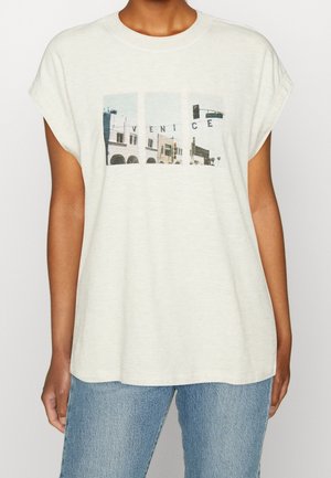 Lyse beige grafisk t-shirt lavet af blødt stof med et rektangulært tryk, der viser Venedig med blå og grå accenter. Kortærmet.