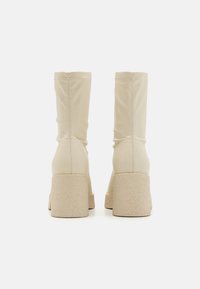Beiga ankelboots i ett slätt material med en texturerad chunky sula. Har skaft som sitter tätt och minimal sömdetaljering.