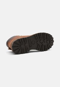 Stivale in pelle marrone con suola in gomma nera caratterizzata da treads profondi, design rinforzato e costruzione robusta per una maggiore durata.