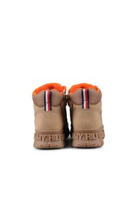 Tan sneakers met oranje bontvoering, voorzien van een dikke rubberen zool, logo-accenten en gemusterde strepen in rood, wit en blauw.
