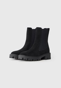 Sorte semskede ankelstøvler med elastiske sidepaneler, rund tå og såle i gummi med serraterte mønstre for godt grep. Klassisk Chelsea-design.