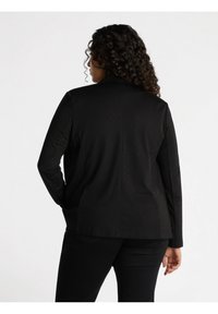 Blazer nero con un design su misura, caratterizzato da una trama di tessuto liscia e un sottile motivo a pois. Include maniche lunghe e un colletto a intaglio.