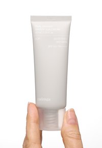 Grå tub med solkräm, matt yta, 40 ml kapacitet, märkt för känslig/torr hud, med genomskinlig botten och vit text. SPF 50+ PA++++.