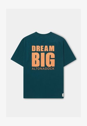 Camiseta de algodón color azul verdoso oscuro con un gran gráfico naranja que muestra el texto "DREAM BIG" y "ALTONADOCK" en la parte trasera, mangas cortas.