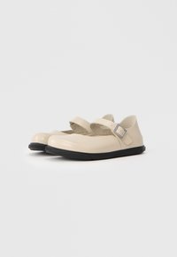 Scarpe Mary Jane in plastica beige con punta arrotondata, suola piatta in gomma nera e una fascia abbinata con una fibbia argentata.